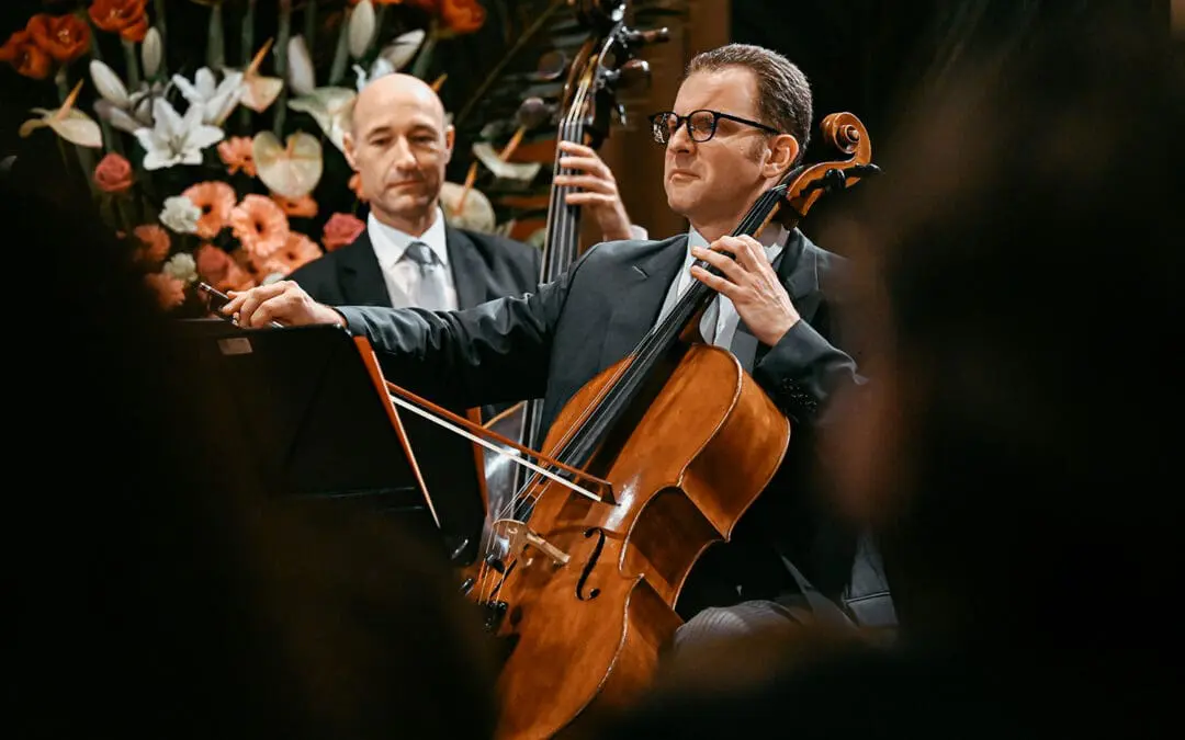 Cellist und Kontrabassist vor Blumenschmuck spielend